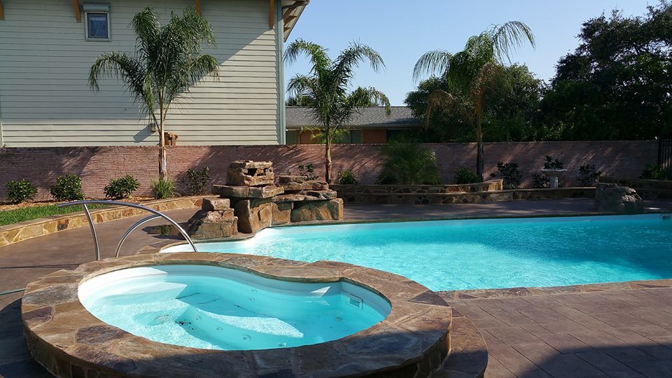 A serene pool featuring a hot tub and a natural rock wall, creating a tranquil outdoor retreat.